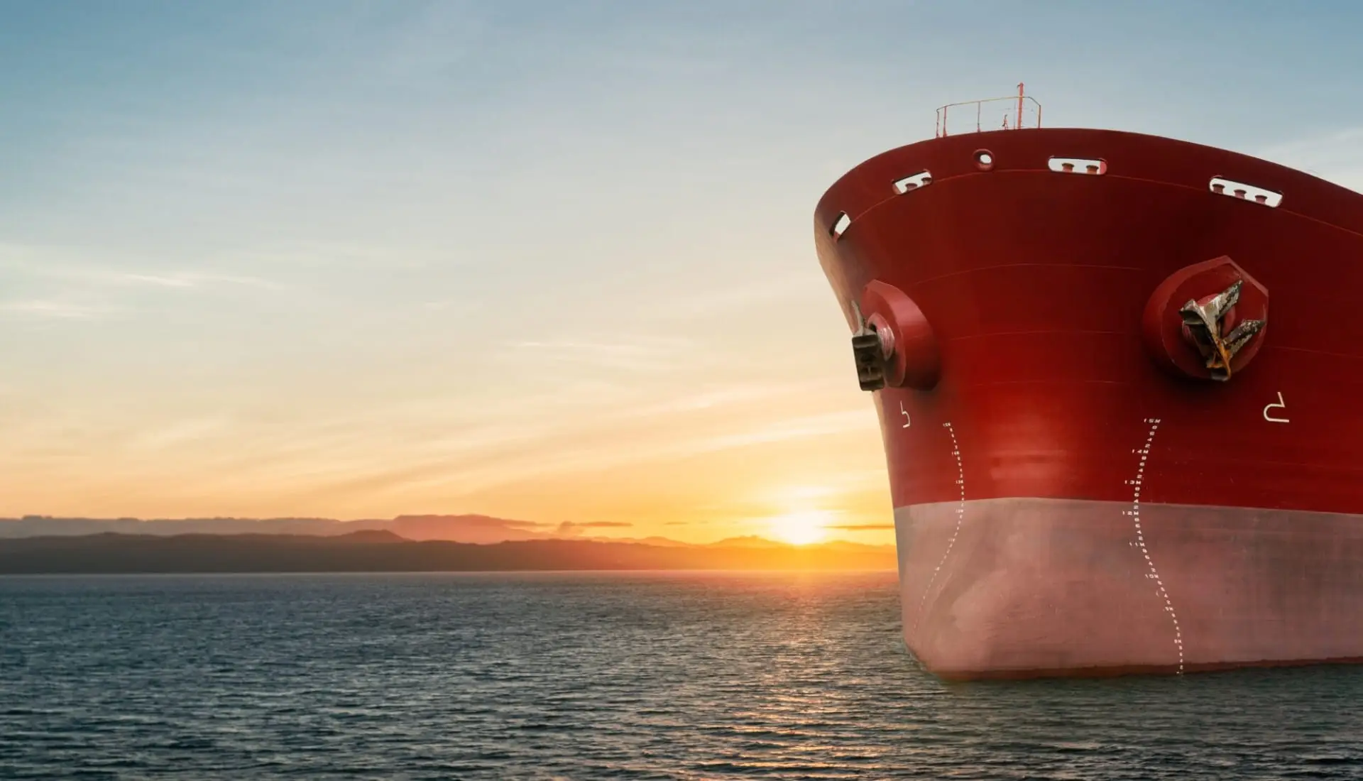 Rött fartygsskrov med bulbstäv i solnedgång